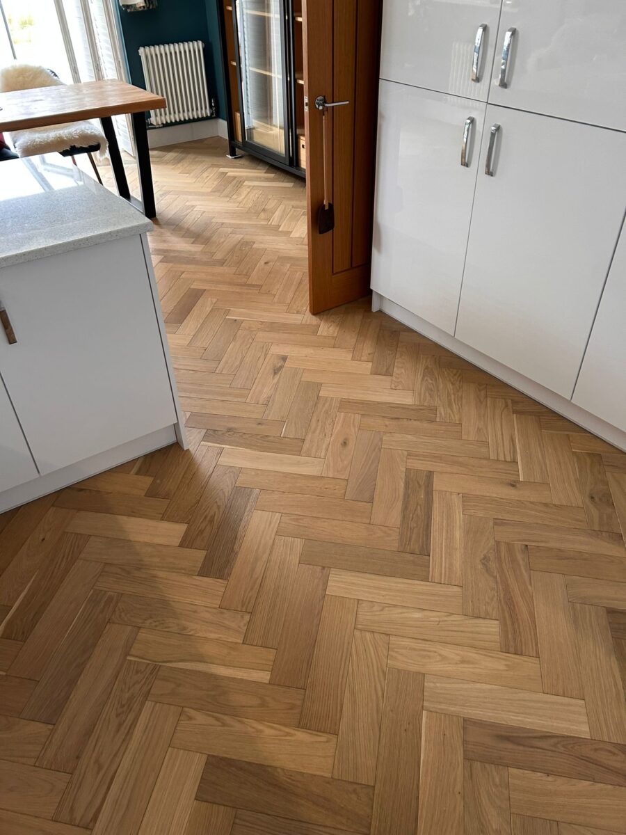 Natural oak engineered wood flooring in a classic herringbone parquet pattern installed in a modern kitchen by Avana Flooring.